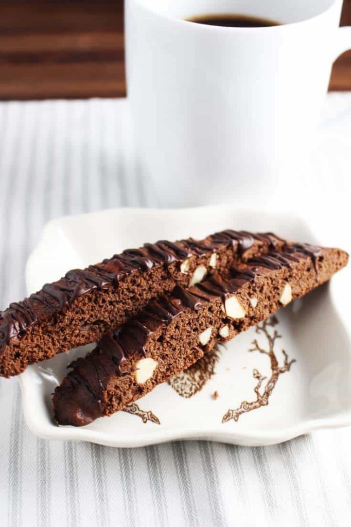 Two almond chocolate biscotti on a plate with a cup of coffee