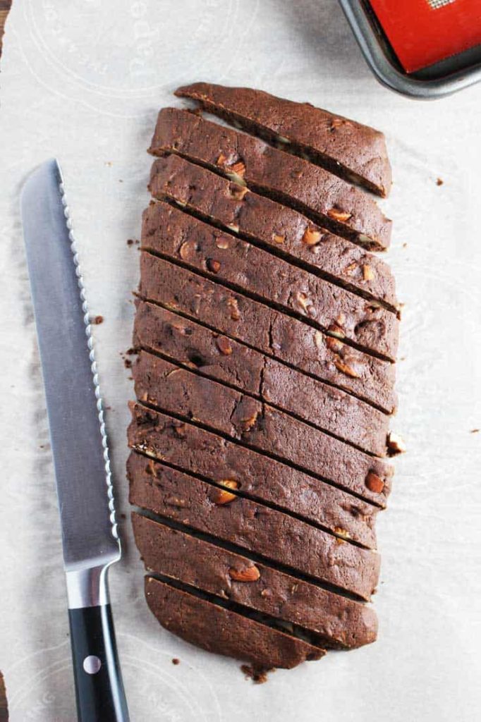 A sliced log of almond chocolate biscotti on parchment