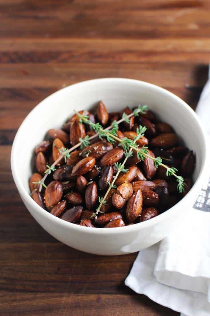 Roasted almonds in a bowl with thyme sprigs