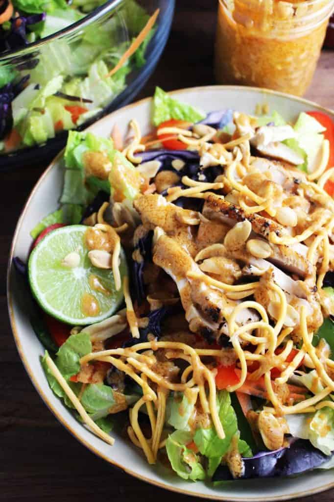 Closeup view of Asian chicken salad tossed with sriracha peanut dressing in a bowl