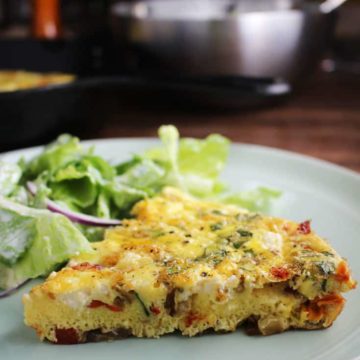 Side view of a slice of easy fritatta recipe on a plate with salad.