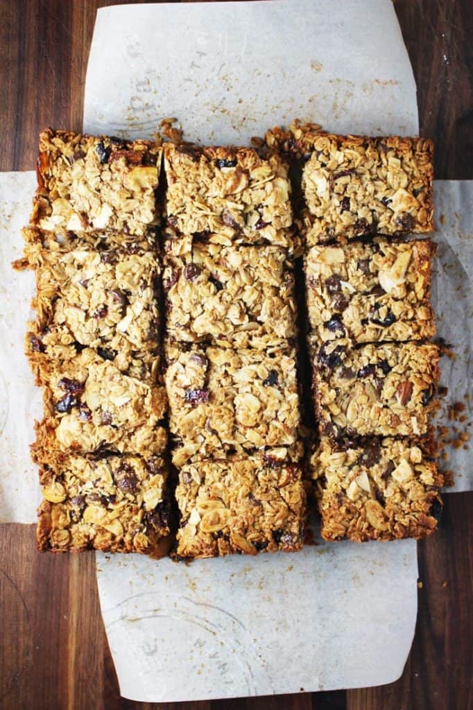 Freshly baked chewy granola bars cut into squares on a sheet of parchment