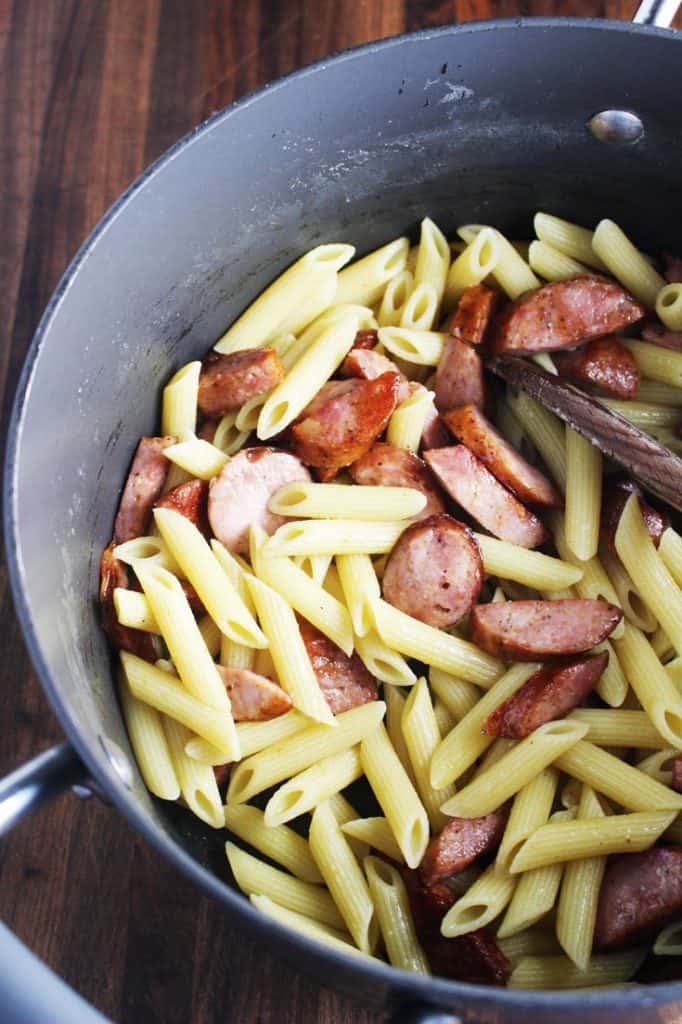 Cooked pasta and sausage mixed together in a pot for sausage and vegetable pasta skillet