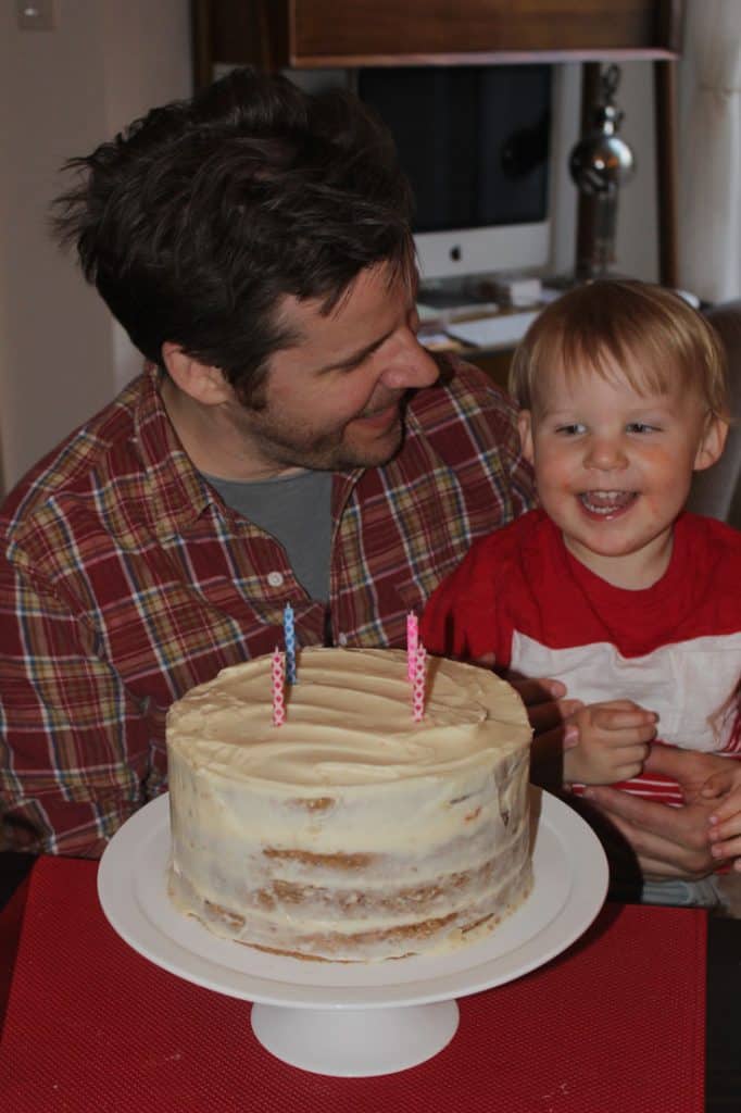Father and son with a moist carrot cake birthday cake with candles