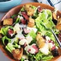 Caesar salad recipe with steak in a wooden bowl
