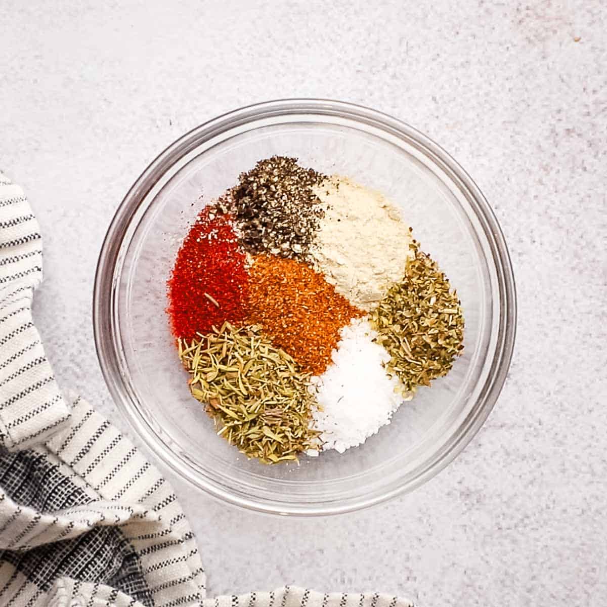 A bowl with spices used to make a Cajun seasoning.