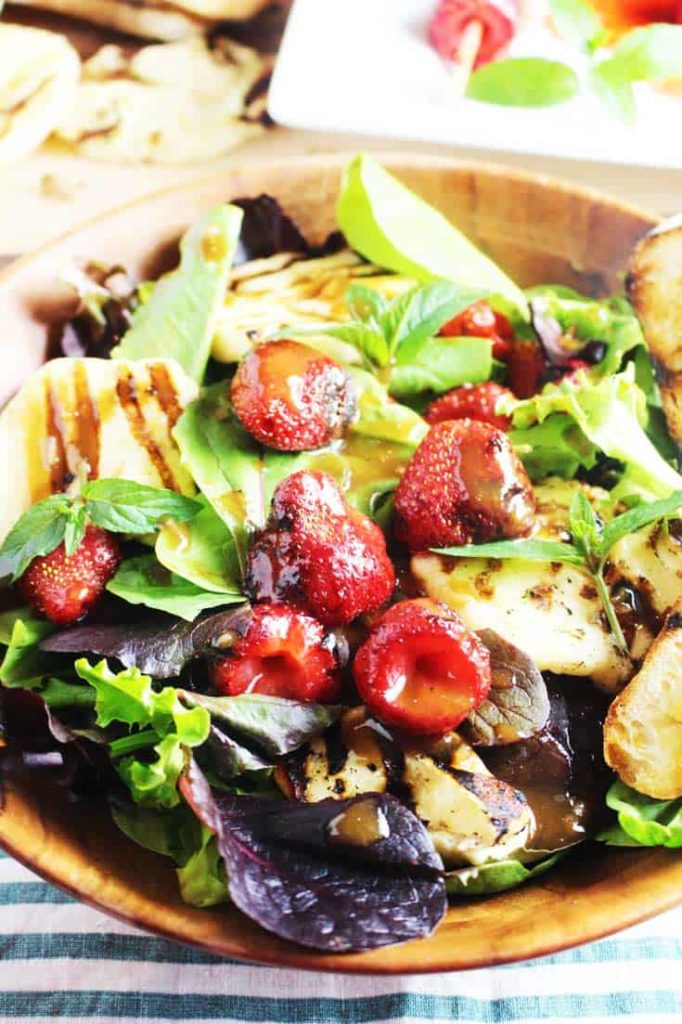 Grilled halloumi and strawberry salad in a wooden bowl