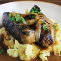 bangers and mash with gravy in a shallow bowl