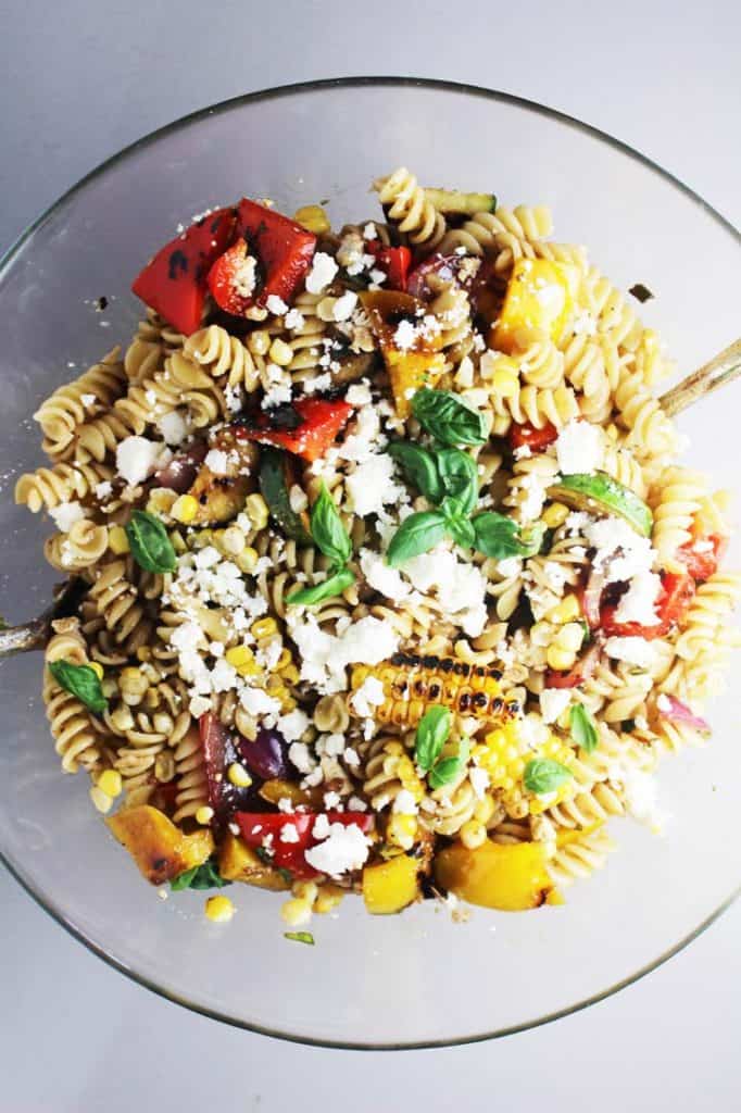 Summer pasta salad with grilled vegetables in a large glass serving bowl 
