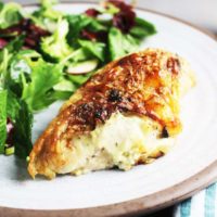 A Roasted chicken breast stuffed with Boursin cheese on a plate with salad