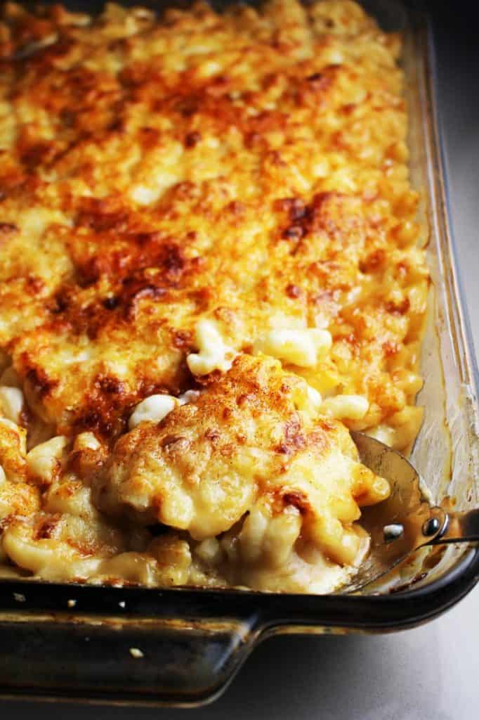 Baked macaroni and cheese in a glass baking dish with a portion scooped out