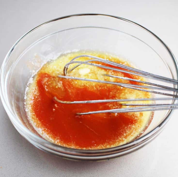 Hot sauce being whisked with butter for Buffalo chicken breast burgers