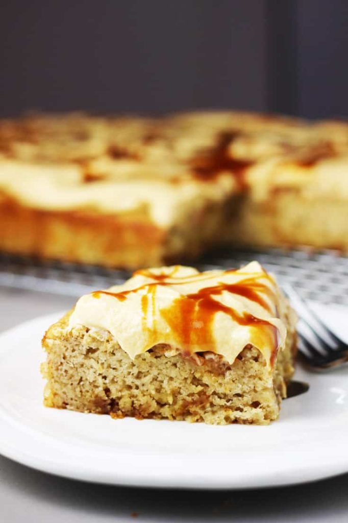 a piece of banana caramel cake with caramel frosting on a white plate