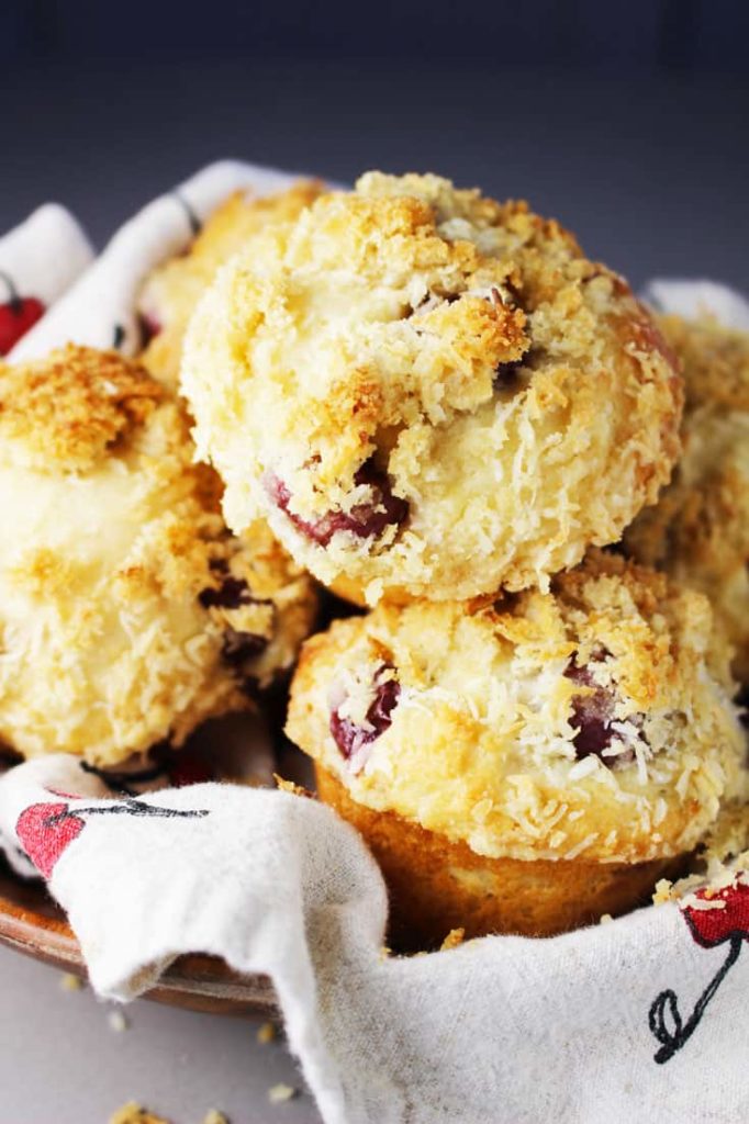Sour cherry muffins with coconut streusel piled into a wooden bowl