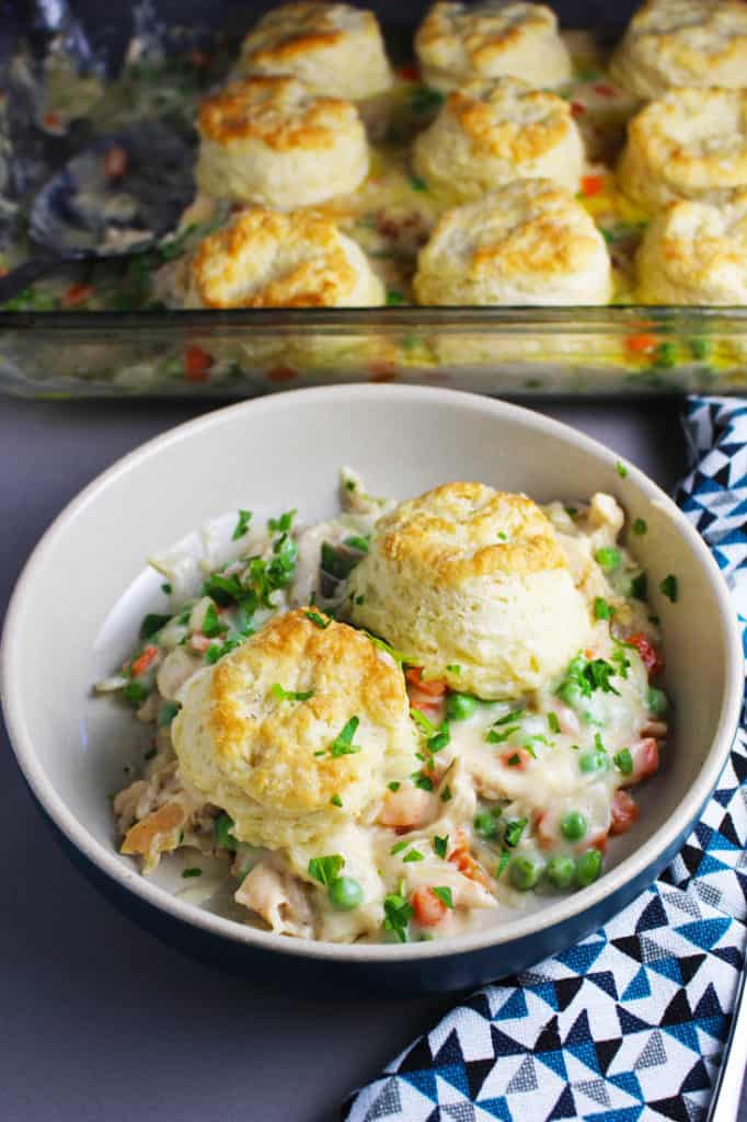 A bowl of chicken and biscuits with peas and carrots