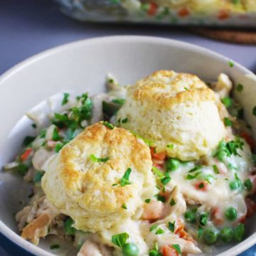 A bowl of chicken and biscuits with peas and carrots