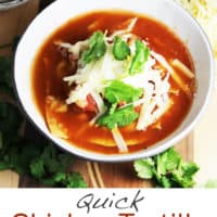 Chicken tortilla soup in a bowl topped with tortilla chips, cheese, sour cream and cilantro