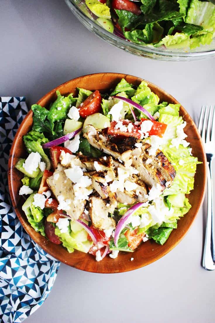 Tossed green Greek chicken salad in a wooden bowl