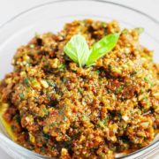 a bowl of sun dried tomato pesto garnished with basil leaves