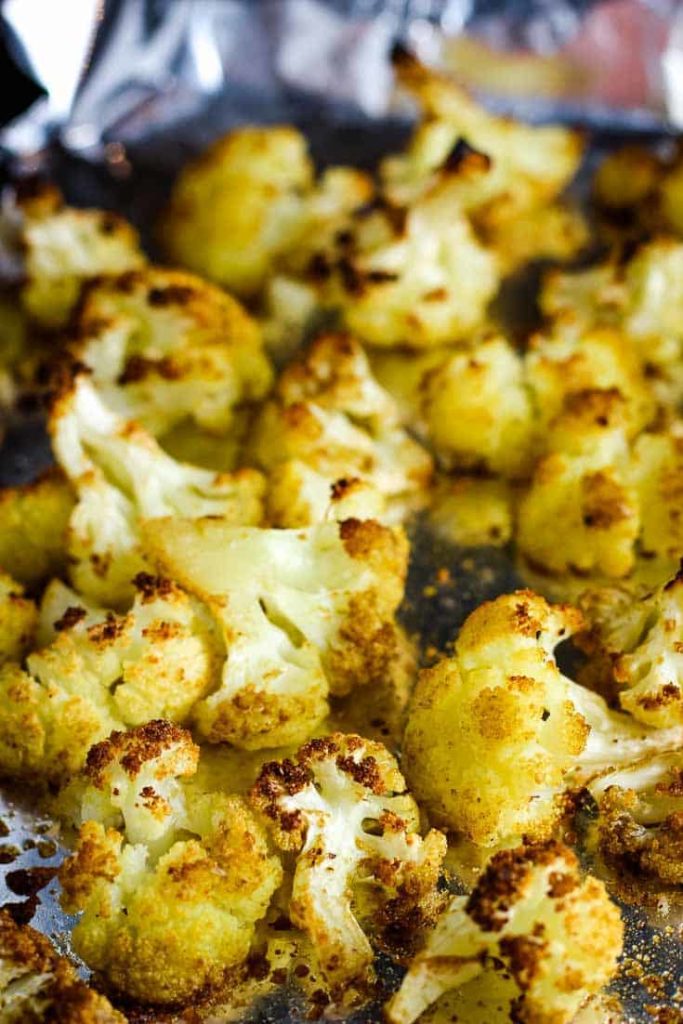 Roasted cauliflower florets on a foil-lined baking sheet