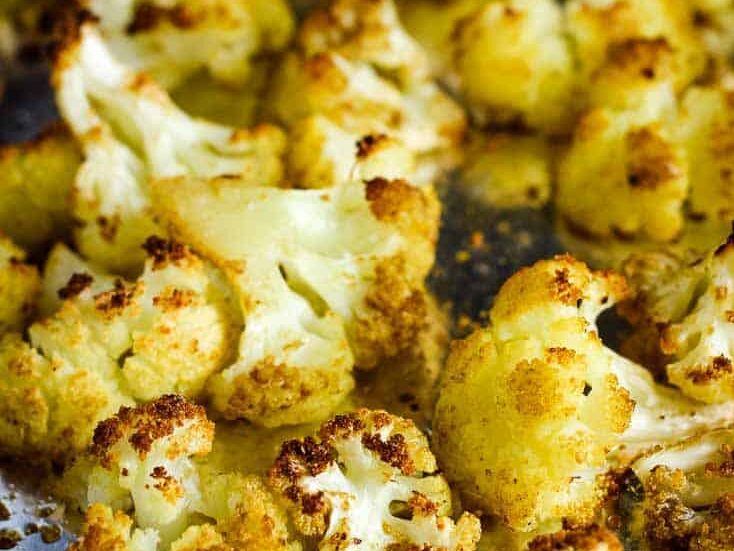 Roasted cauliflower florets on a foil-lined baking sheet