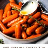A bowl of glazed carrots with a sprig of thyme