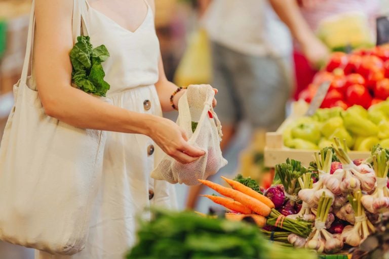 Woman picking produce and putting it into a reusable bag