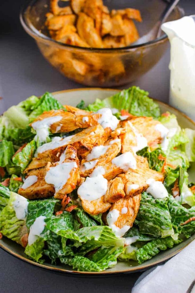 A bowl of buffalo chicken salad topped with ranch dressing