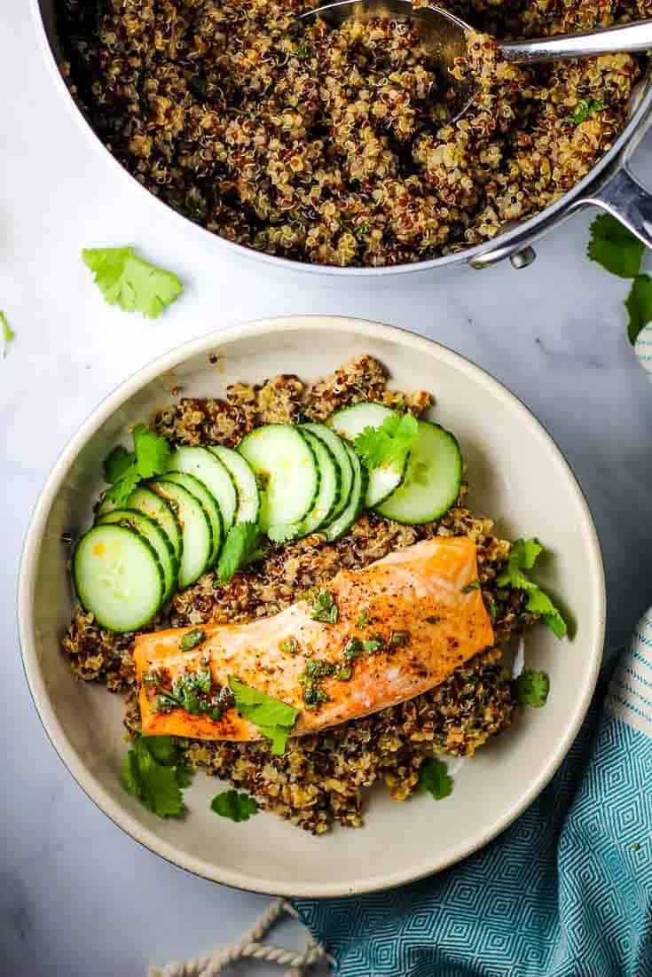 A roasted salmon fillet on a bed of quinoa with cucumber slices