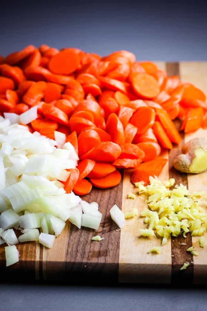 Chopped carrots, onions and ginger on a cutting board