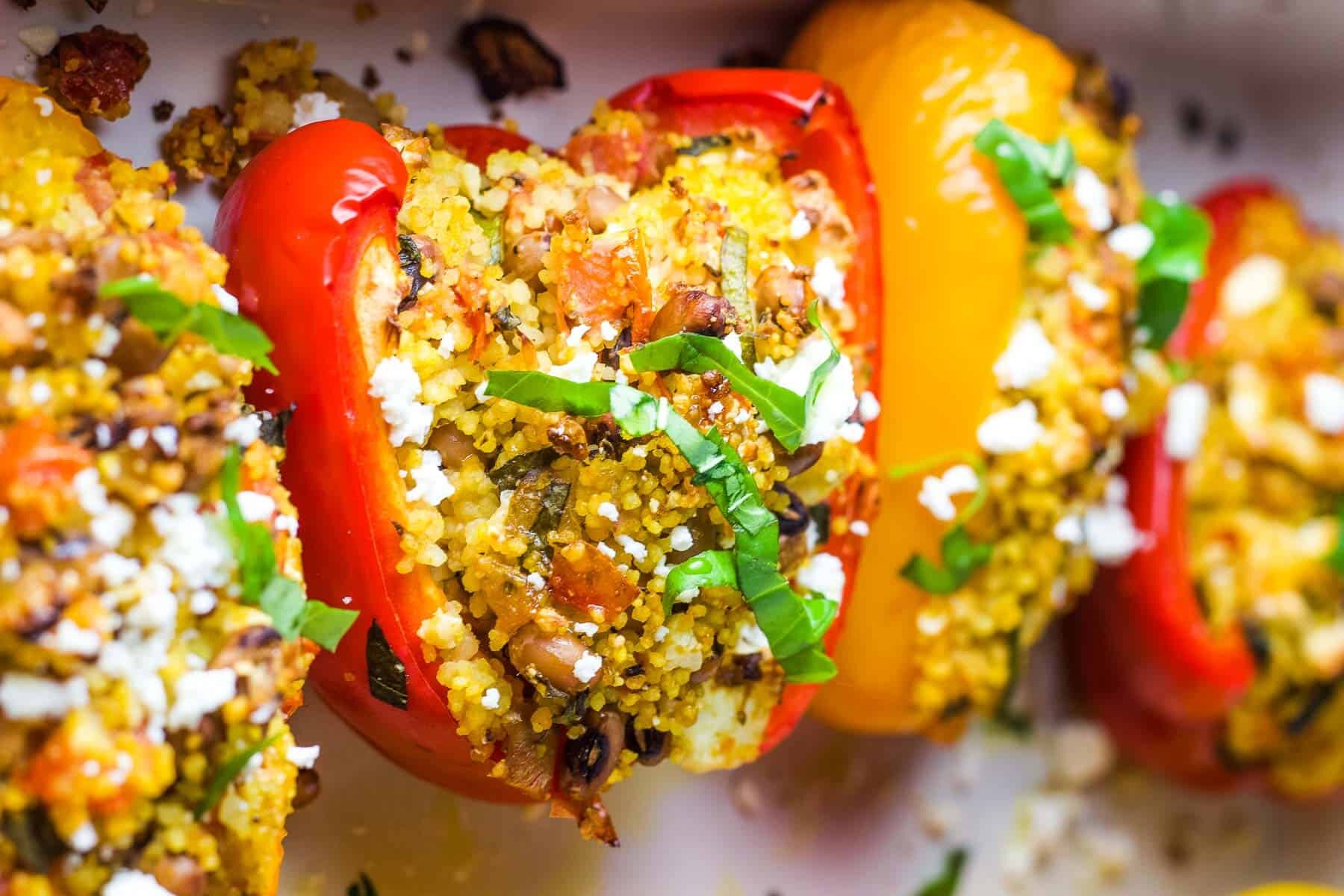 Stuffed bell peppers sprinkled with basil in a baking dish