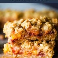 Two peach and raspberry oatmeal bars stacked on top of parchment paper with text overlay