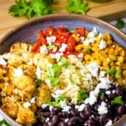 A bowl of vegetables and beans on a be of rice