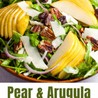 Slice pears arranged on a bed of arugula with pecans, shaved parmesan and sliced red onions.