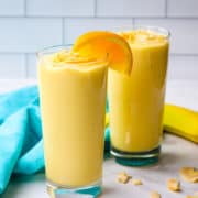 Two mango pineapple smoothies in tall glasses