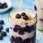 A jar of blueberry overnight oats topped with fresh berries and sprinkled with cinnamon.