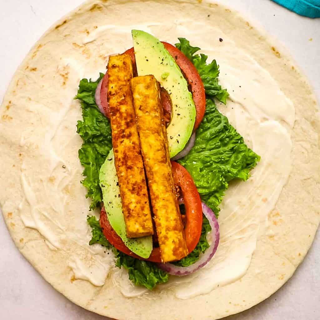 Tofu sticks and vegetables placed on a tortilla.