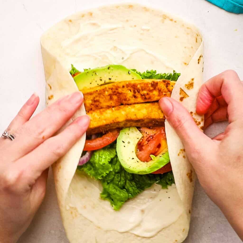 Folding a tortilla wrap filled with ingredients.