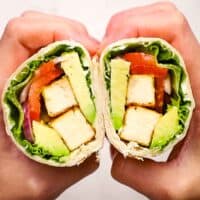 two hands holding and showing the inside of a tofu wrap