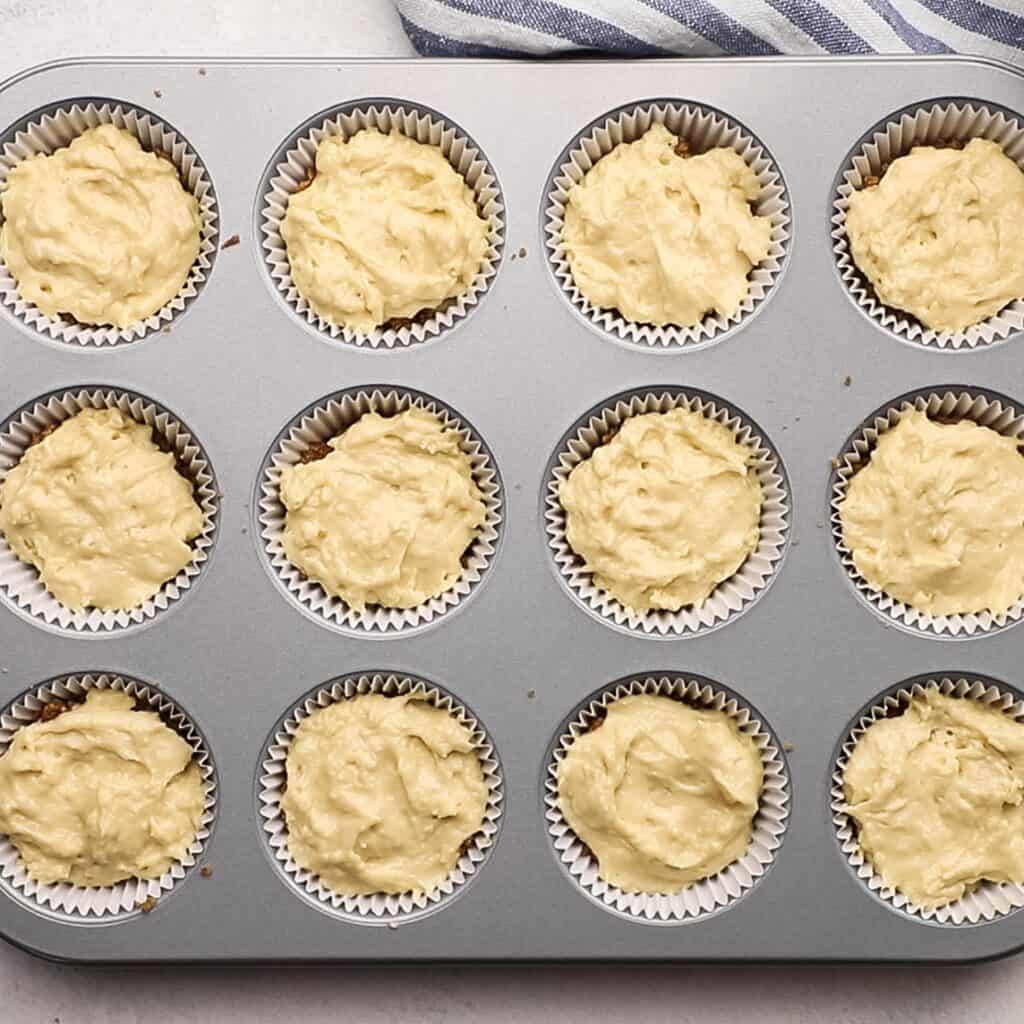 a second layer of muffin batter on top of filling in a muffin tin.