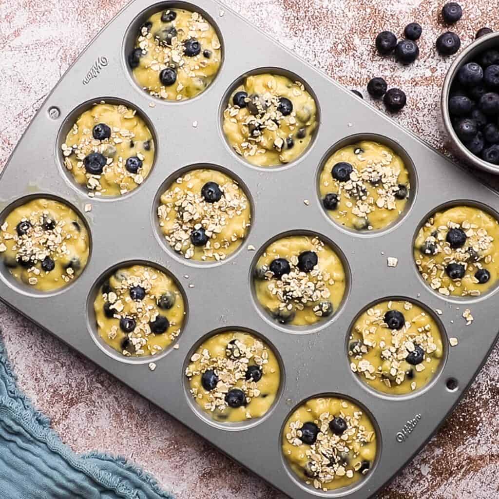 Blueberry muffin tins lined with blueberry muffin batter.