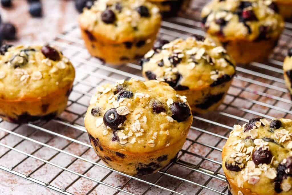 Blueberry banana muffins stacked on a cooling rack.
