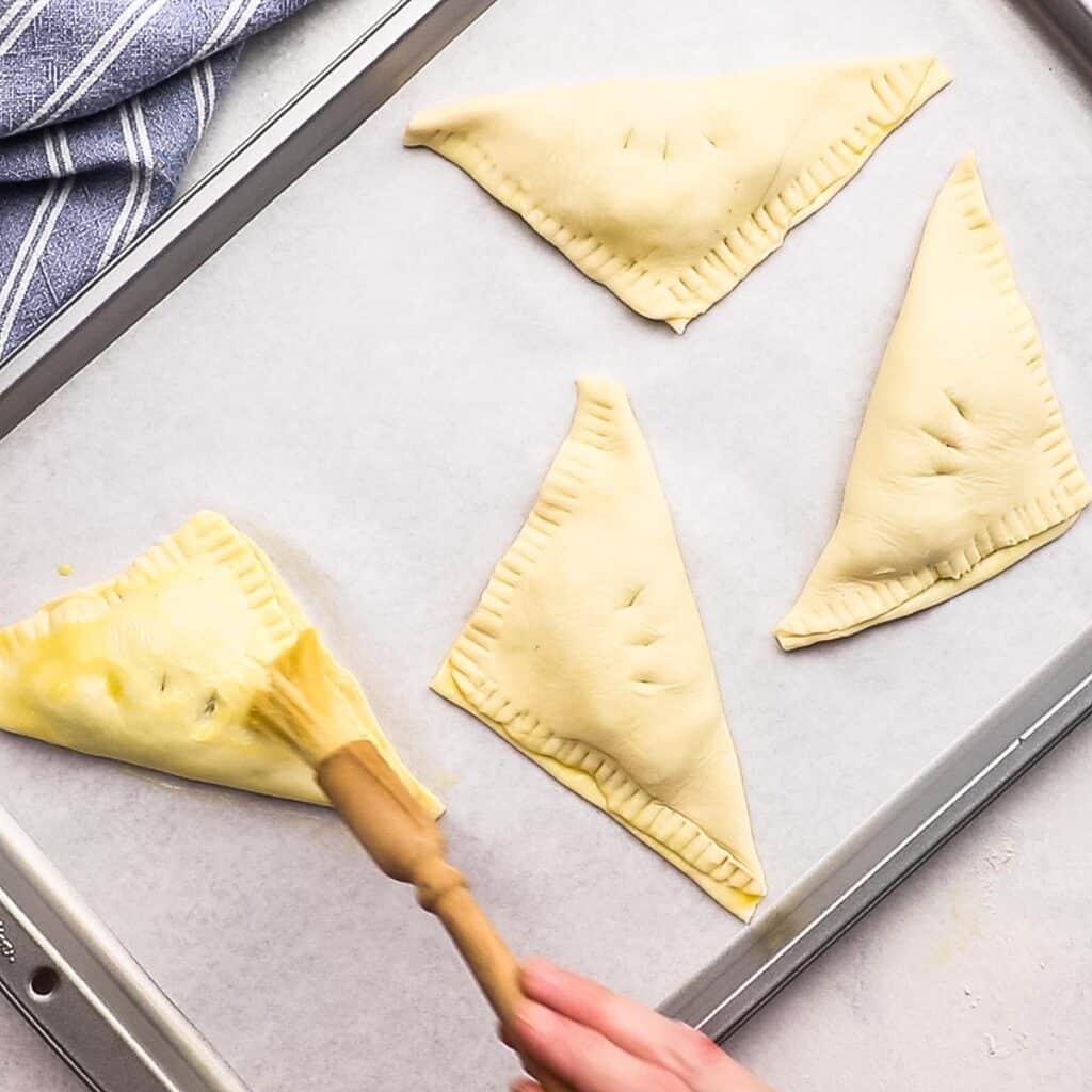 Brushing egg wash on a strawberry turnover.