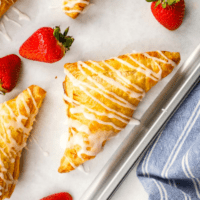 Freshly baked strawberry turnovers on a baking sheet.