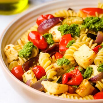 A bowl of halloumi pasta garnished with pesto