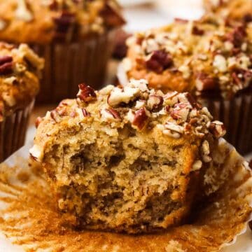 A banana pecan muffin, cut in half to show the inside, sitting on top of a muffin liner.