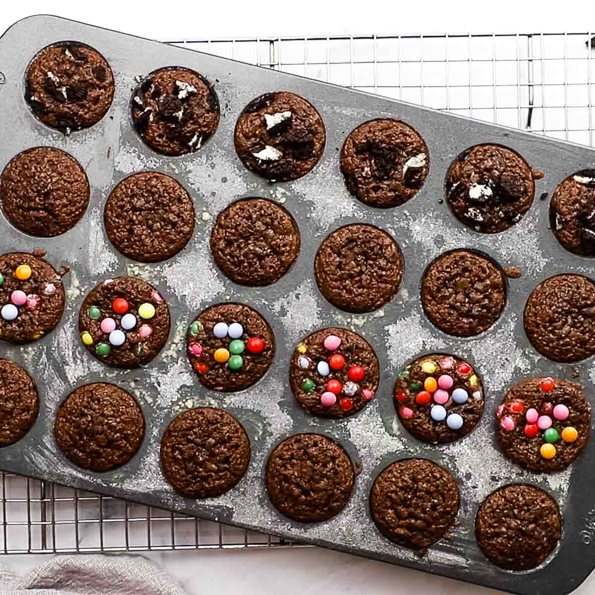 Pan of baked mini brownies with a variety of toppings.