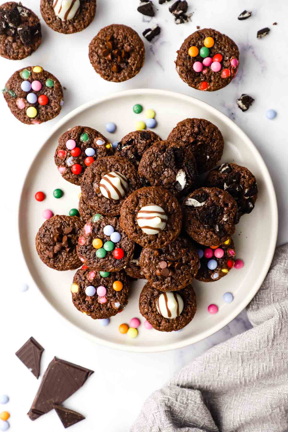 Overhead view of a plate of mini brownies stacked on one another with a variety of toppings.