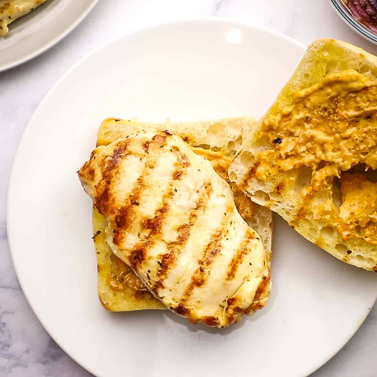 placing grilled chicken on the ciabatta roll