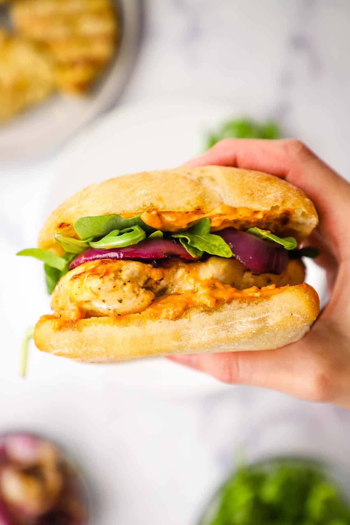 closeup shot of a grilled chicken sandwich in hand